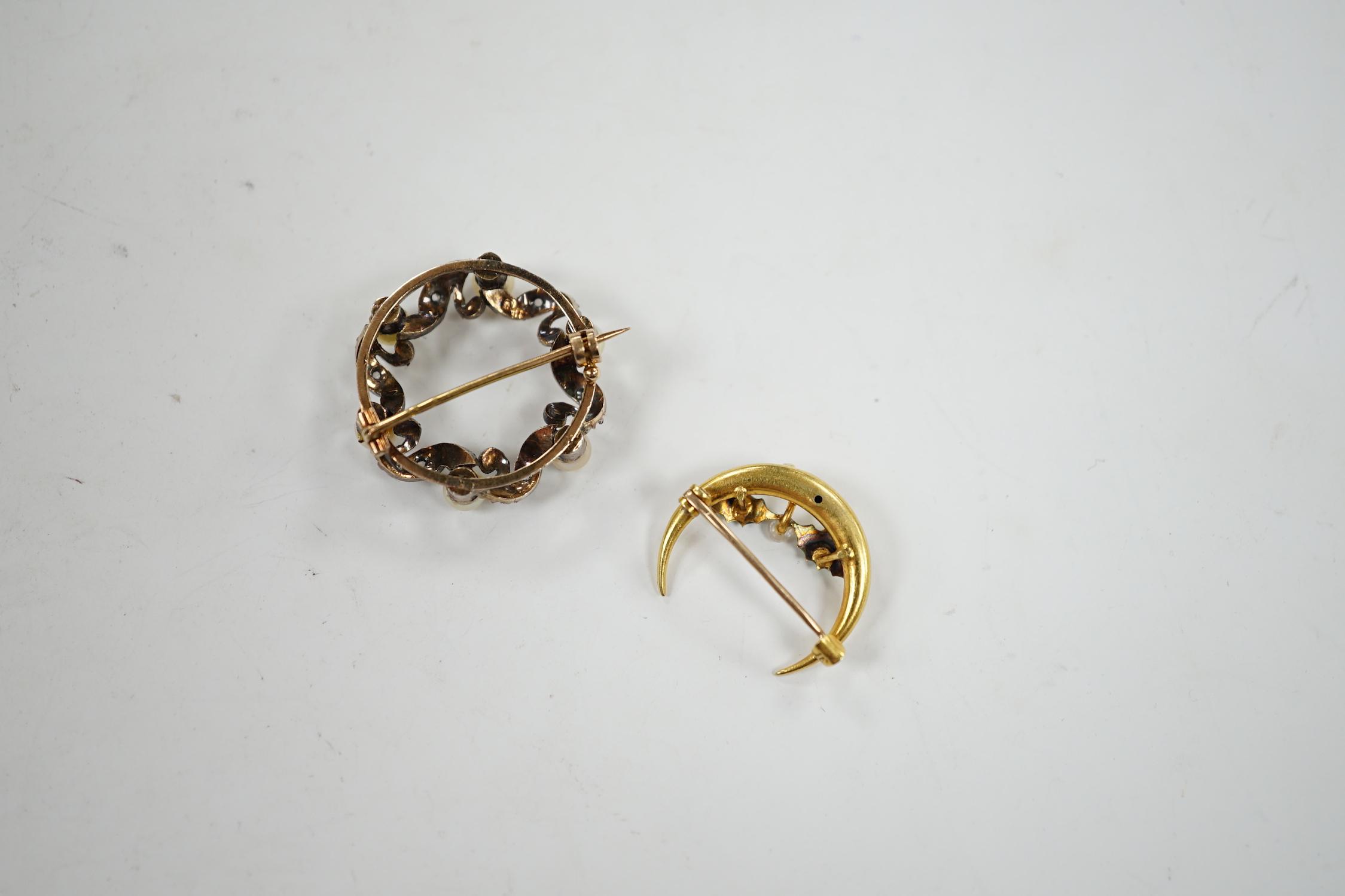 A yellow metal enamel and small baroque pearl set folate crescent brooch, 27mm, together with a yellow metal, cultured pearl and diamond chip set openwork circular brooch.